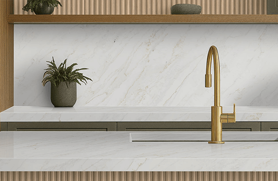 Kitchen featuring a Calacatta Premata creamy marble-like quartz countertop and matching backsplash, with a gold faucet and natural wood accents.
