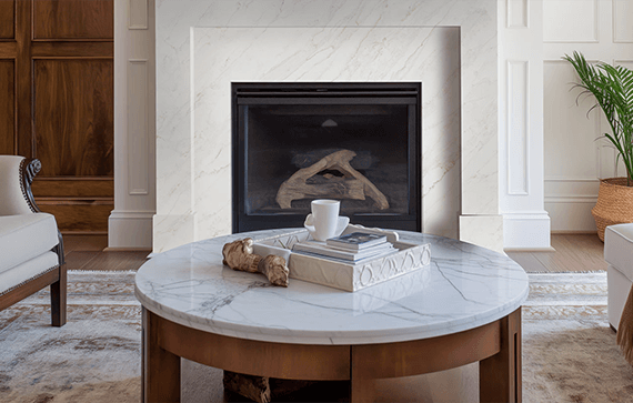 Elegant living room featuring a custom fireplace with a Calacatta Premata Premium Natural Quartz surround, showcasing its white marble-like appearance and subtle veining.