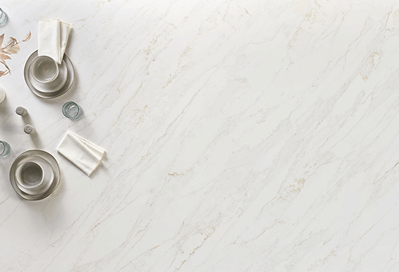Overhead view of Calacatta Premata Premium Natural Quartz countertops, showcasing subtle grey veining on a pristine white background, adorned with elegant dishware.